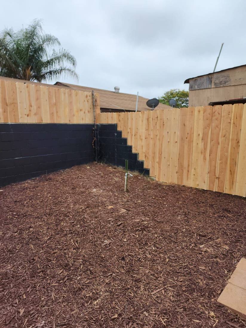 New wood fence built on top of a painted block wall — Benitez Tree Service