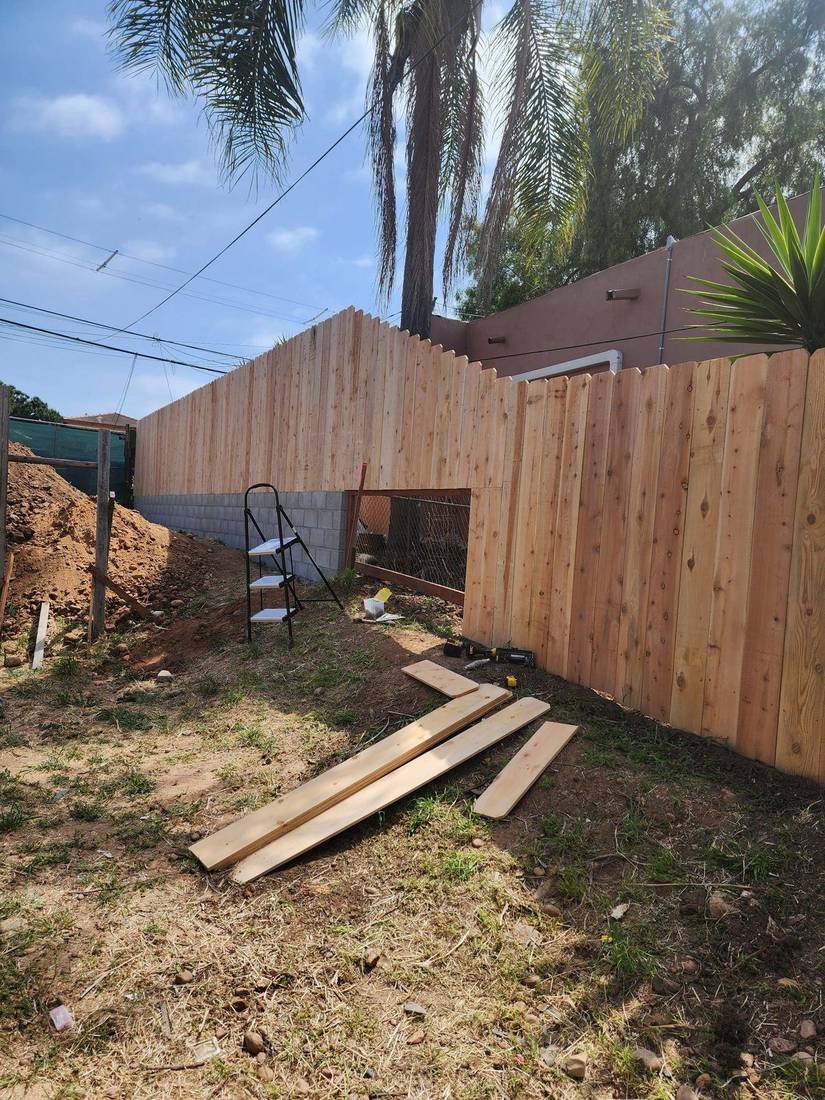 Tall cedar wood fence installed along a sloped property — Benitez Tree Service