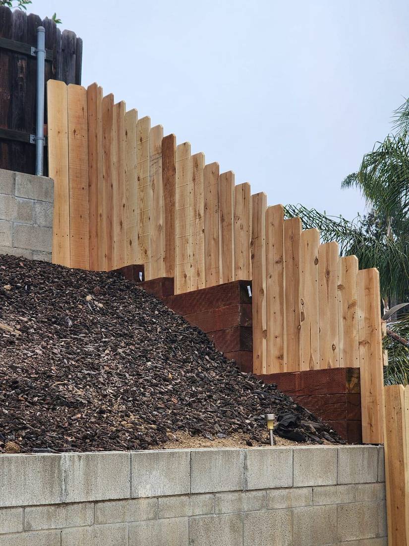 Stepped cedar fence over a retaining wall, built by Benitez Tree Service in San Diego